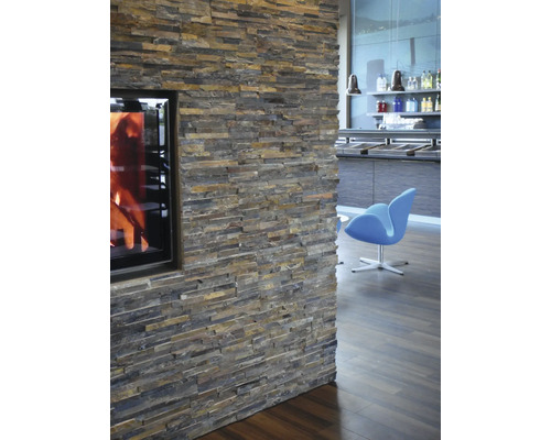 Vägg med naturstensbeklädnad och öppen spis i vardagsrummet.