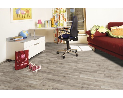 Barnrum med ljust trägolv, skrivbord och röd soffa.