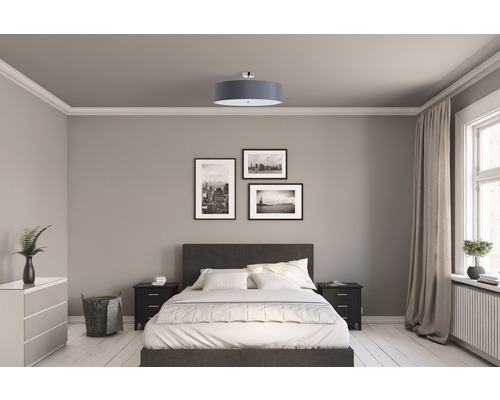 Sovrum med säng, sängbord, byrå, taklampa och väggdekorationer