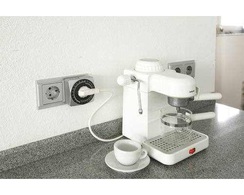 Timer i uttag bredvid kaffebryggare med kopp