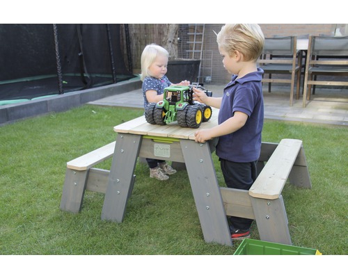 Barn leker vid ett picknickbord i trä i trädgården.