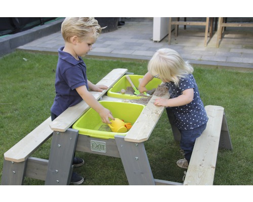 Två barn leker vid ett EXIT sand- och vattenbord utomhus.