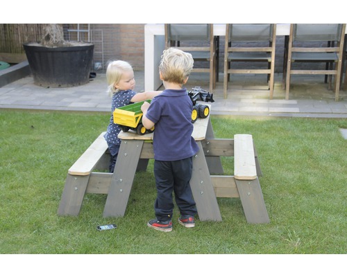 Barn leker vid en grå barnmöbelgrupp i trädgården.