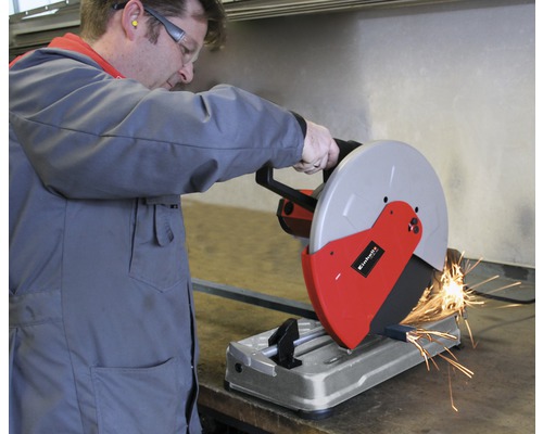 En man använder en metallkap för att skära en metallbit. Det flyger gnistor.