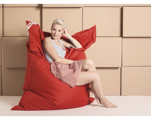 Kvinna sitter avslappnad i en röd sittsäck framför kartonger.