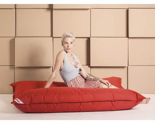 Kvinna sitter på röd sittsäck framför flyttkartonger