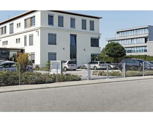 Dubbelstavs stängsel framför en byggnad med parkerade bilar