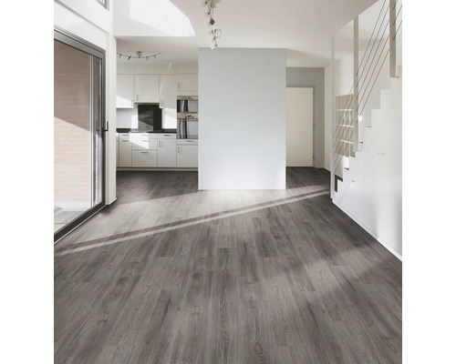 Ljust vardagsrum med grått trägolv, trappa och pentry