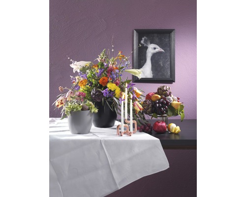 Dekoration med blomsterarrangemang, fruktskål, ljus och en inramad bild av en vit påfågel.