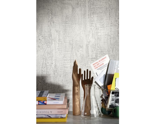 Dekorativ scen med böcker, handdekorationer i trä och erlenmeyerkolv framför en väggtapet.