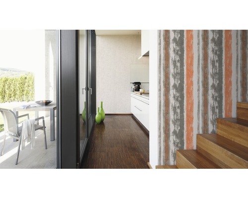 Ljust rum med trappa, tapet med randigt mönster, kök och terrass i bakgrunden