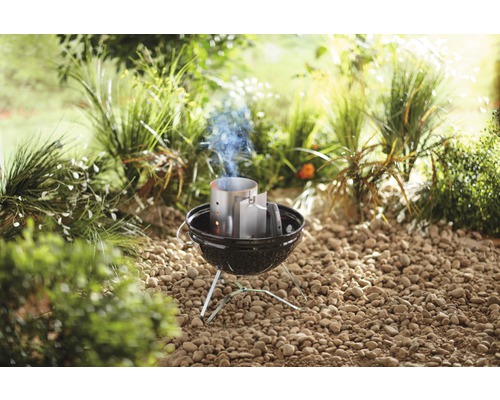 Liten grill med skorstenständare i trädgården