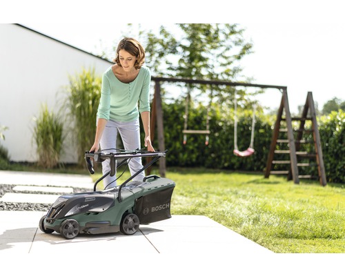 Kvinna förbereder en Bosch gräsklippare i trädgården
