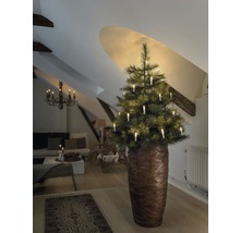 Julgran med ljus i ett vardagsrum under ett sluttande tak