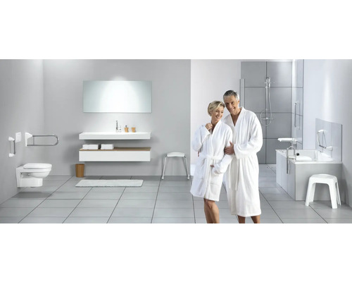 Tillgängligt badrum med toalett, handfat, badkar och stödhandtag för ökad säkerhet.