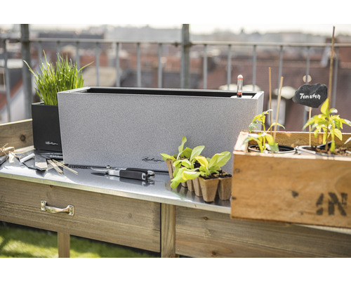 Scen med planteringsbord, blomlådor och trädgårdstillbehör för utomhusbruk.