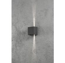 Kubisk vägglampa av metall med ljusstrålar uppåt och nedåt