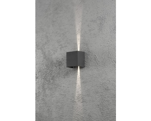 Kubisk vägglampa av metall med ljusstrålar uppåt och nedåt