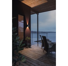 Scen av en träterrass med en utomhusvägglampa, stolar och utsikt över en sjö