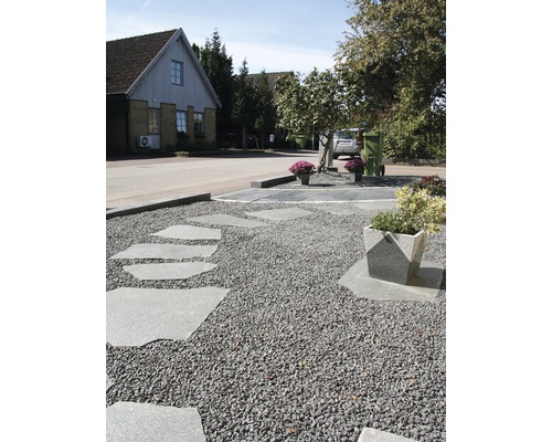 Utomhusbild med grusgång och trampstenar framför ett hus