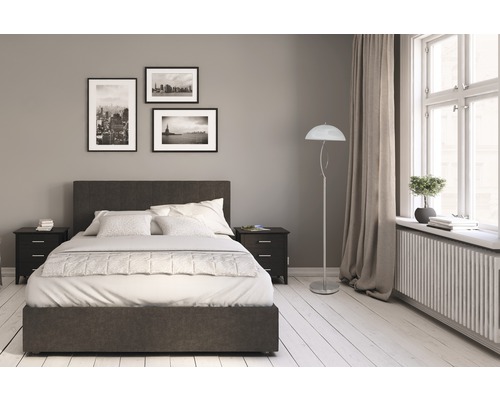 Sovrum med säng, sängbord, golvlampa och bilder