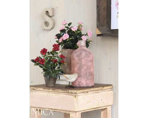 Dekorativ scen med konstgjorda blommor, fågel och vas på ett bord