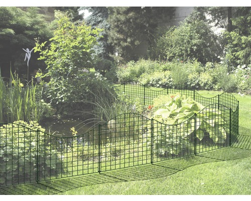 Trädgård med ett lågt stängsel som omger en blomsterrabatt