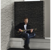 Scen med man som spelar elgitarr framför en väggpanel med steneffekt