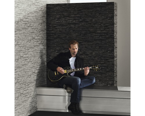 Scen med man som spelar elgitarr framför en väggpanel med steneffekt