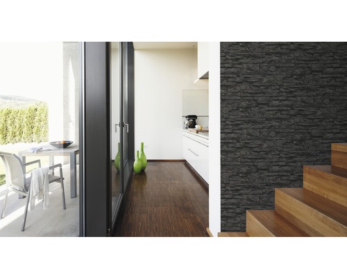 Ljust rum med en vägg i stenlook, trappa och utsikt över en terrass