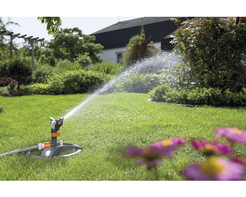 Trädgårdsspridare vattnar gräsmattan i trädgården.