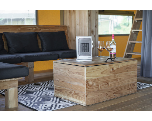 Interiörvy med värmefläkt, vinflaska och vinglas på ett träbord bredvid en sittgrupp