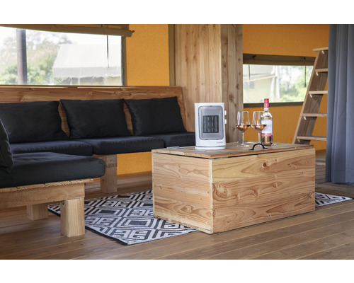 Interiör av ett tält med trämöbler, en värmefläkt och en vinflaska med glas