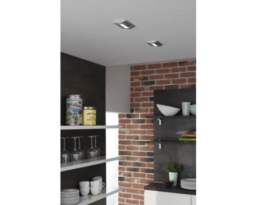 Köksscen med takspotlights, tegelvägg och öppna hyllor med porslin