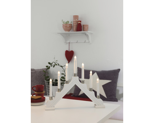 Vit adventsljusstake i trä med sju LED-ljus på ett bord med dekorationer
