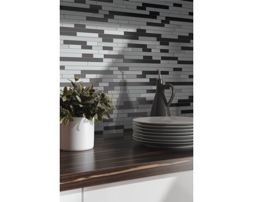 Vägg med mosaikplattor ovanför en köksbänk med porslin och dekoration