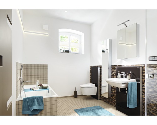 Ljust badrum med badkar, toalett, handfat och spegelskåp