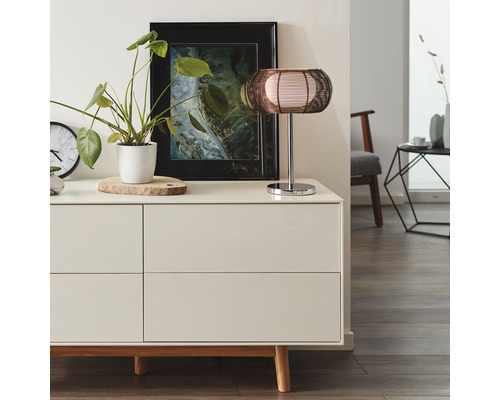Sideboard med dekorationer och bordslampa i ett ljust rum