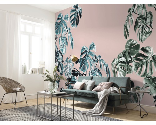Vardagsrum med Monstera-tapet, soffa och rottingfåtölj.