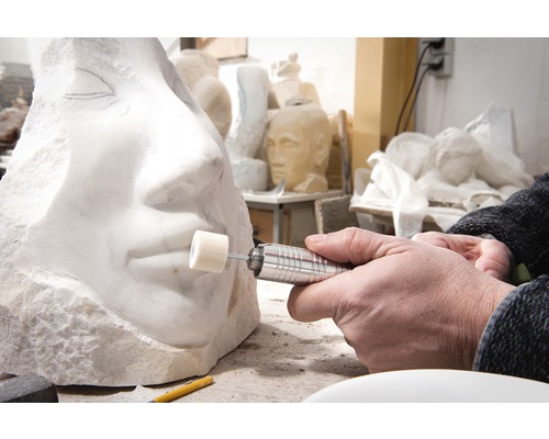 Närbild av en person som skulpterar en stenskulptur med ett roterande verktyg