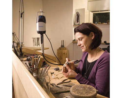 Kvinna arbetar med ett Dremel multifunktionsverktyg på ett arbetsstycke på en arbetsbänk