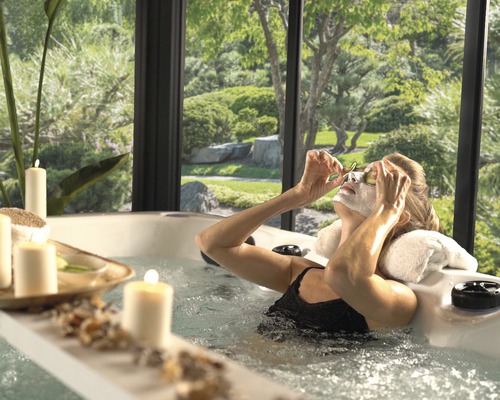 Kvinna kopplar av i en bubbelpool med utsikt över en trädgård