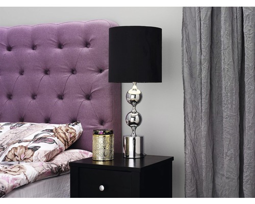 Sovrum med säng, sänglampa och dekoration på nattduksbordet