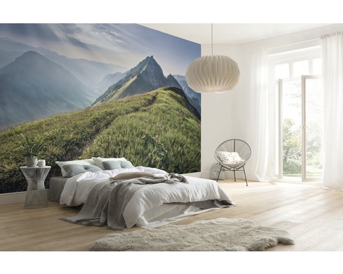 Ljust sovrum med fototapet av bergslandskap, säng, fåtölj, lampa och ljust trägolv