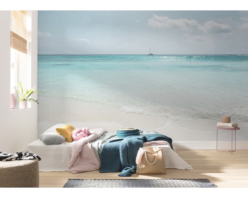 Vardagsrum med fototapet som visar ett havslandskap med strand och en segelbåt.