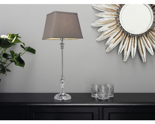 Dekorativ bordslampa med lampskärm på en byrå