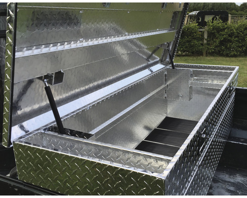 Öppen verktygslåda i aluminium med räfflat mönster på ett lastplan