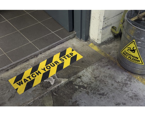 Scen med en skylt som varnar för ett trappsteg och en hink med en varning om våta golv.