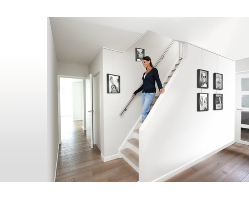 Ljust trapphus med kvinna i trappan och upphängda tavelramar