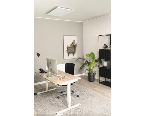 Modernt kontor med värmepanel i taket, höj- och sänkbart skrivbord och förvaringshylla